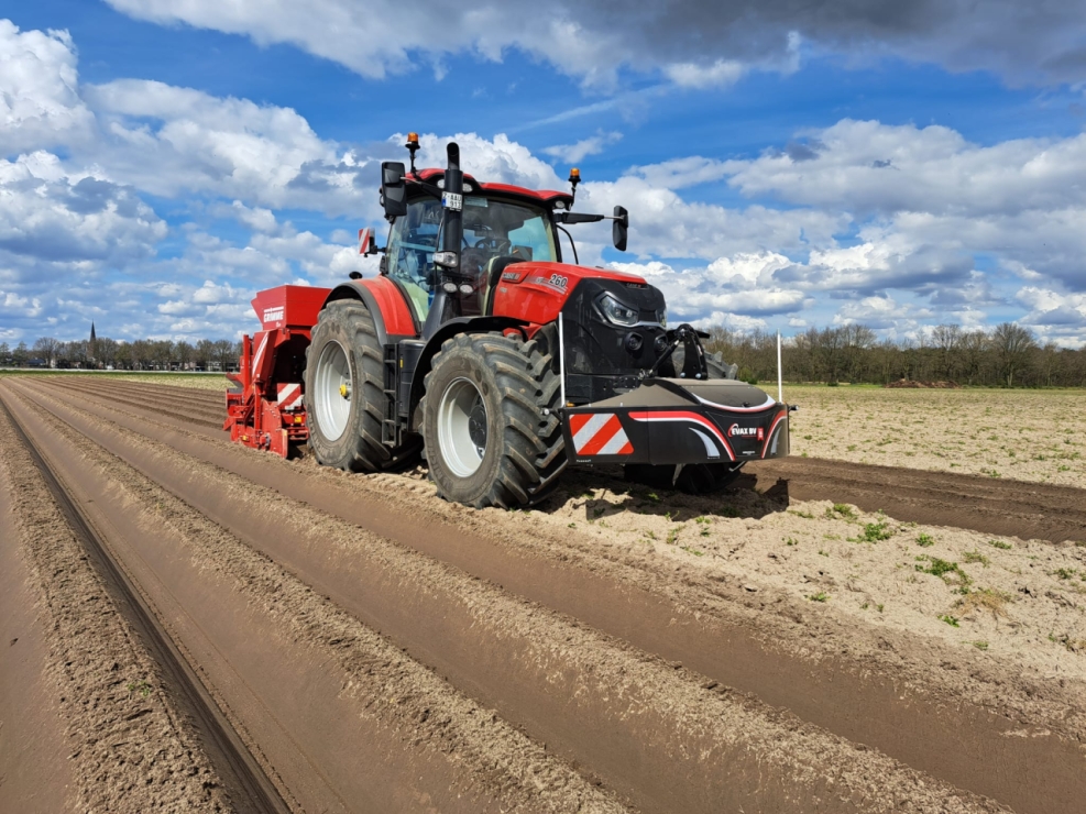 Rode tractor op akkerland met blauwe lucht