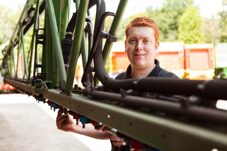 Technicus controleert groene machine onderdelen buiten.