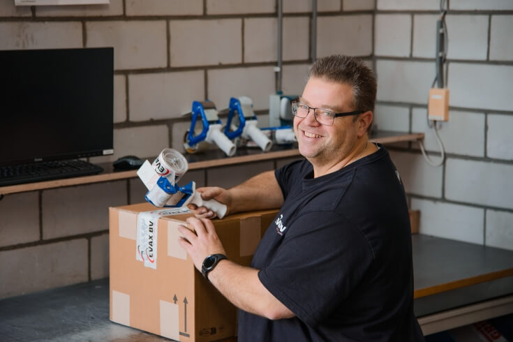 Man verpakt doos met tape in magazijn.