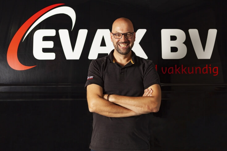 Man voor EVAK BV logo, lachend met gekruiste armen.
