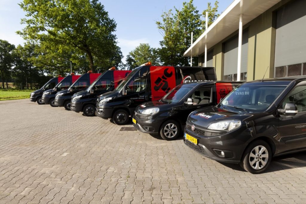 Parkeerplaats met meerdere bedrijfswagens voor loods