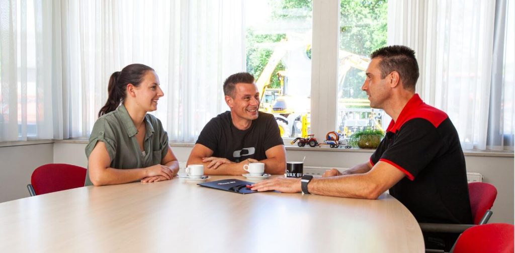 Drie mensen in overleg aan tafel in kantoor