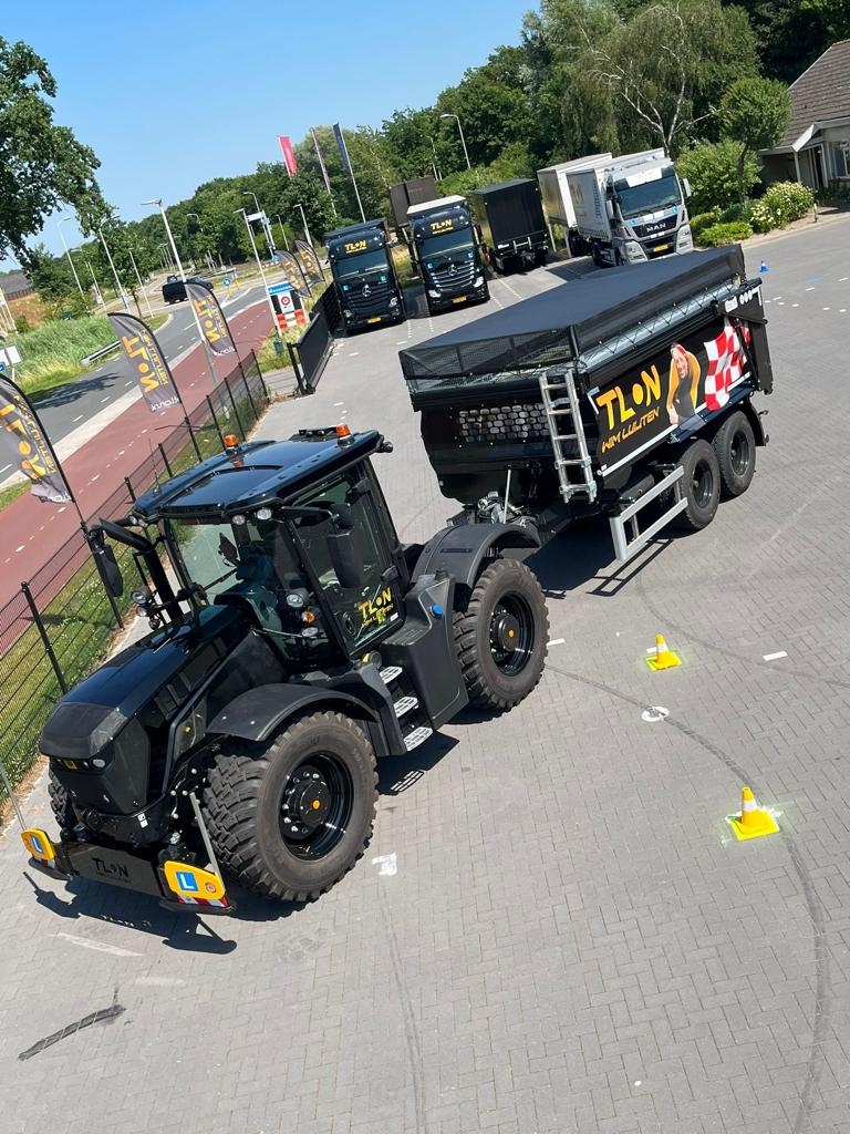 Zwarte tractor met aanhanger op parkeerplaats