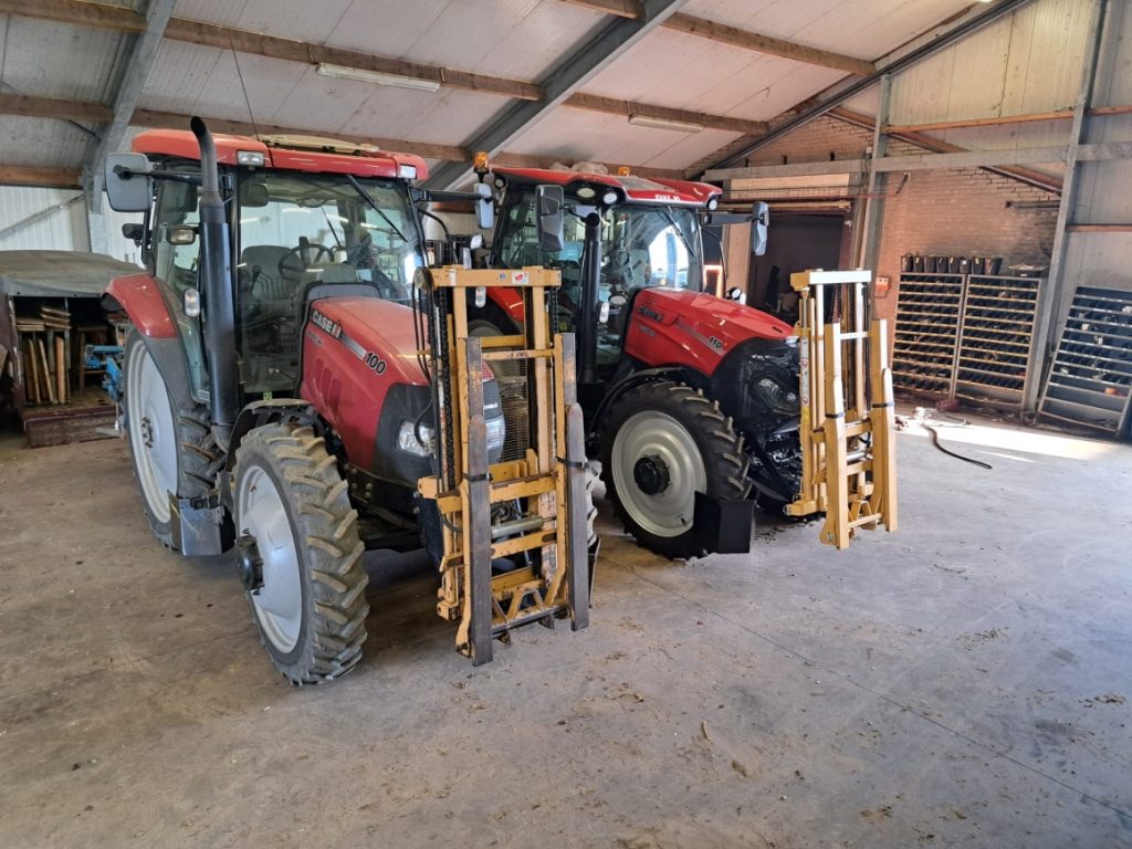 Twee rode tractors in een schuur geparkeerd