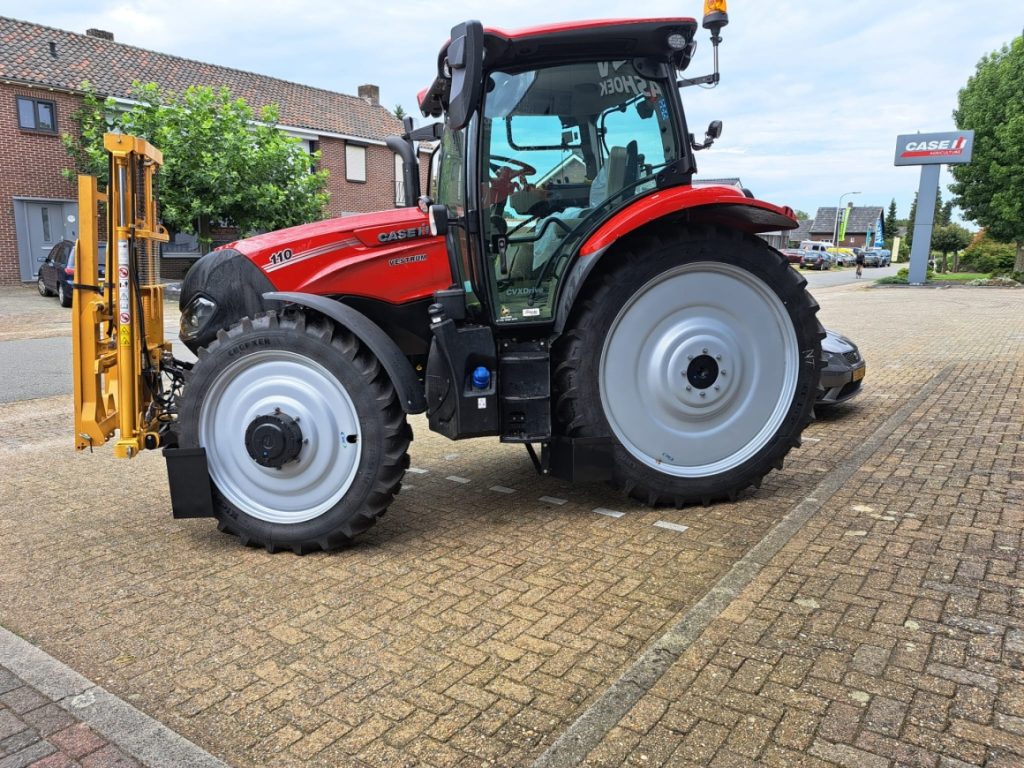 Rode tractor met gele hefboom op straat geparkeerd.