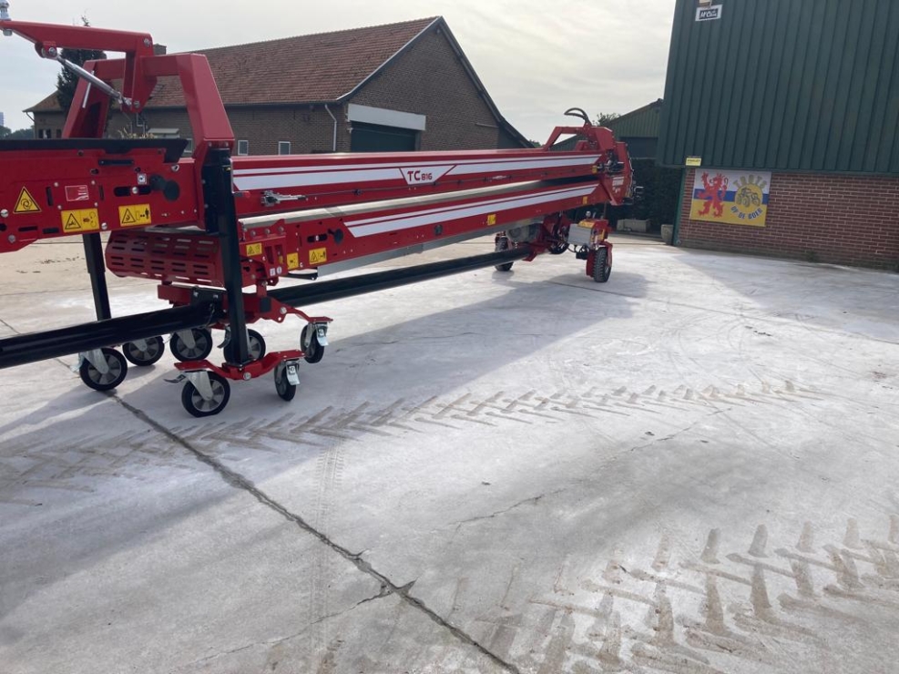 Rode landbouwmachine op erf bij schuur