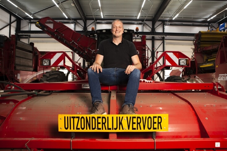 Man zit op landbouwvoertuig met uitzonderlijk vervoer bord.