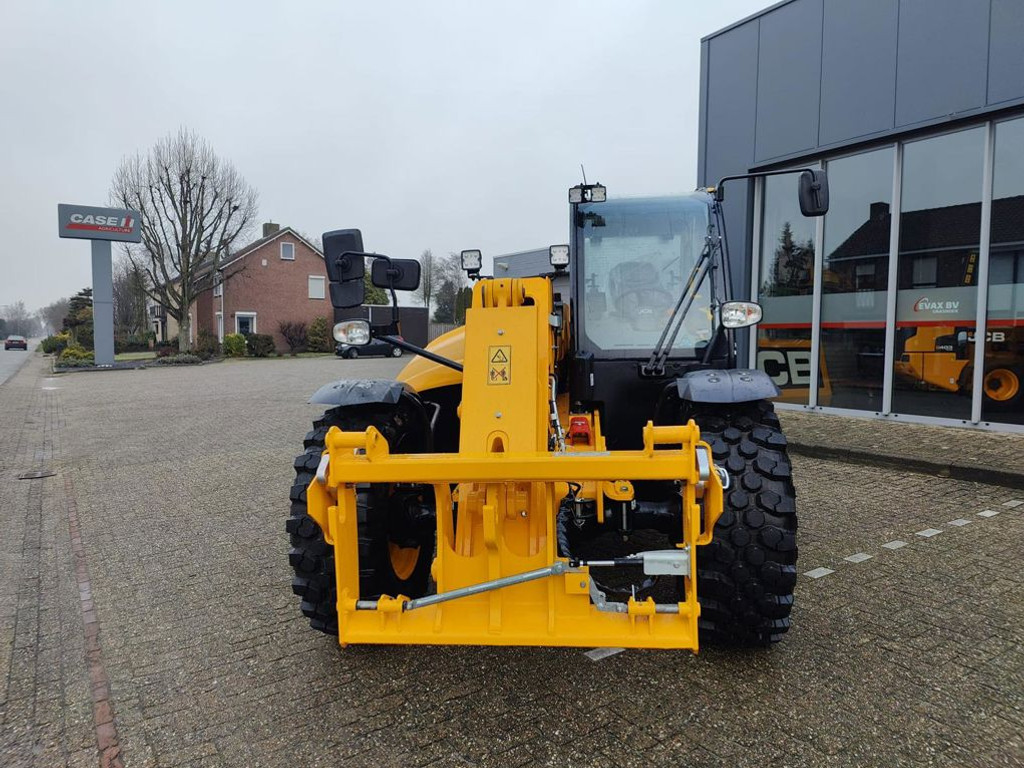 Geel bouwvoertuig geparkeerd voor gebouw.